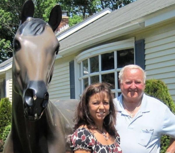 Monique Paone Proulx and Paul Proulx standing outside 1812 Turnpike street, as The Equestrian Shop. There is a large model horse.