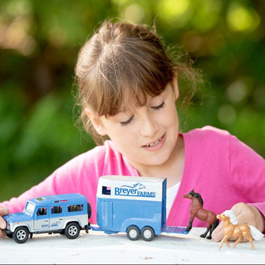 Breyer Stablemates Breyer Farms Land Rover and Tag a Long Trailer being played with by a young girl