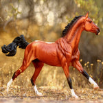 Breyer Traditional Adamek on blurred wooded and grassy background facing right